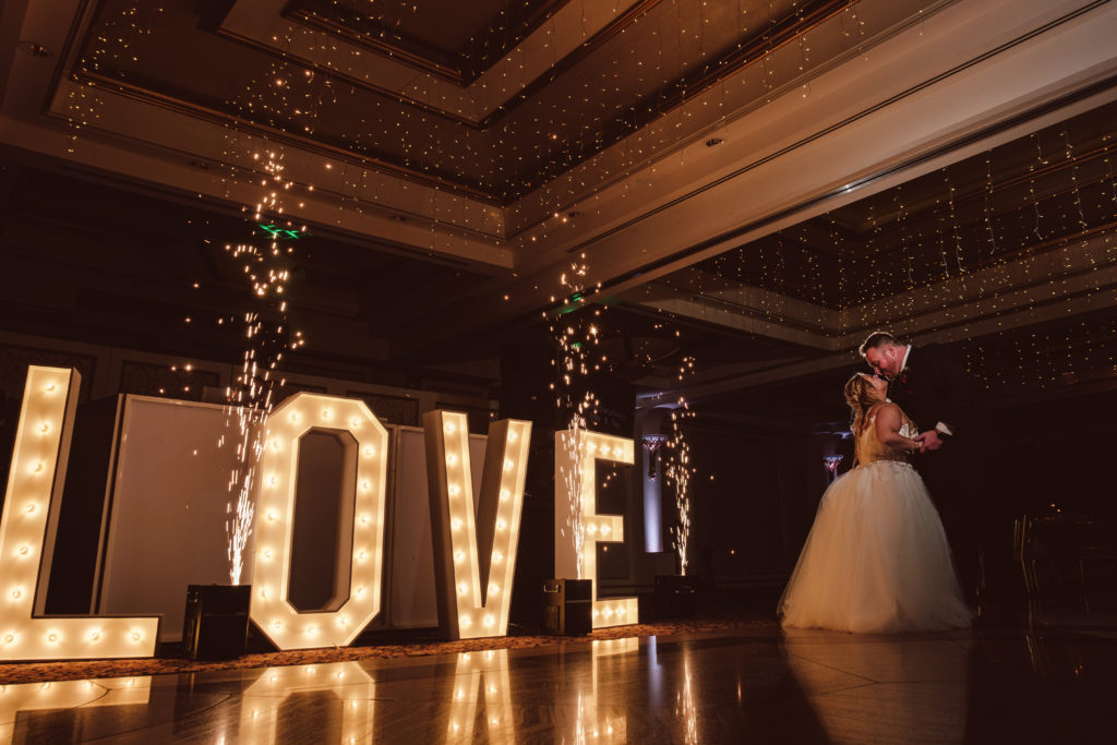 Illuminated 'LOVE' sign and sparklers at wedding.