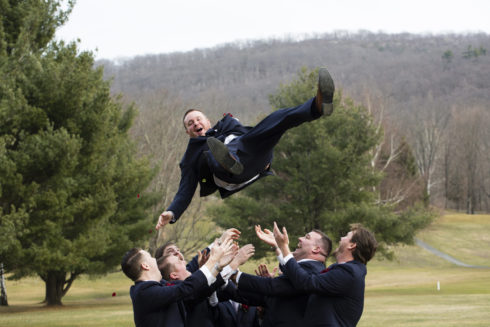groom tossed in the air by groomsmen