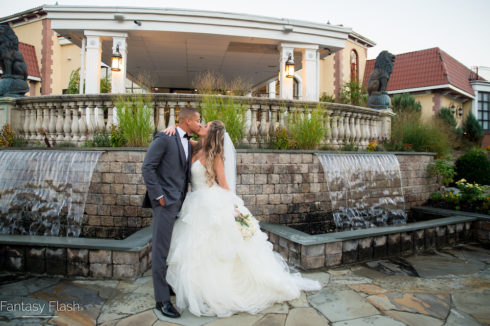 Bride and groom in front of water wall outside Villa Borghese