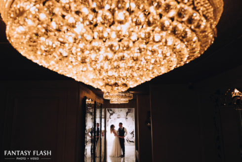 bride and groom posing under chandelier - villa borghese wedding photos