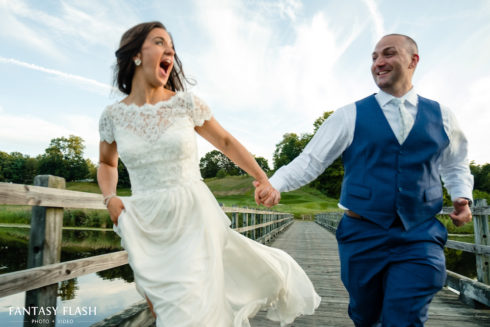 bride and groom running across bridge at Hollow Brook Golf Club