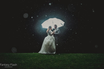a bride and groom under backlit umbrella at the Hollow Brook Golf Club