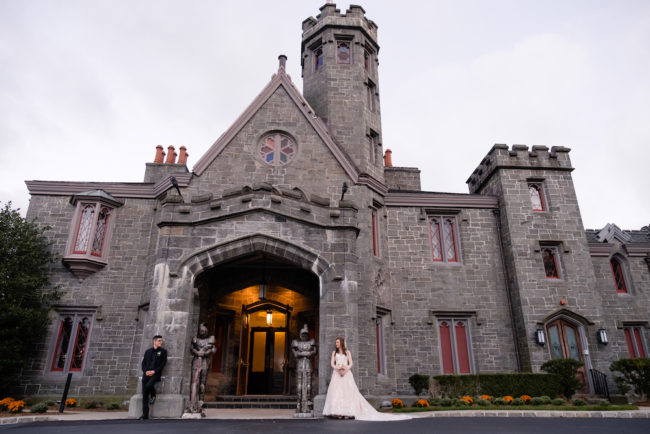 A Bride and groom posing in front of Whitby Castle