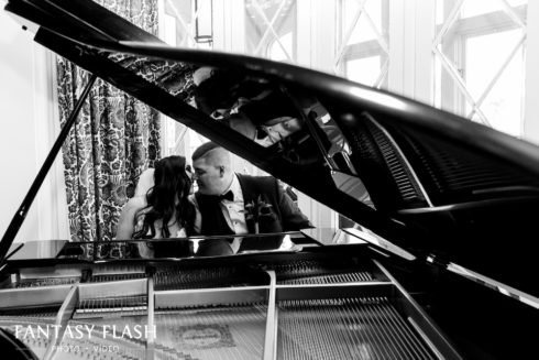 a bride and groom sitting at a grand piano